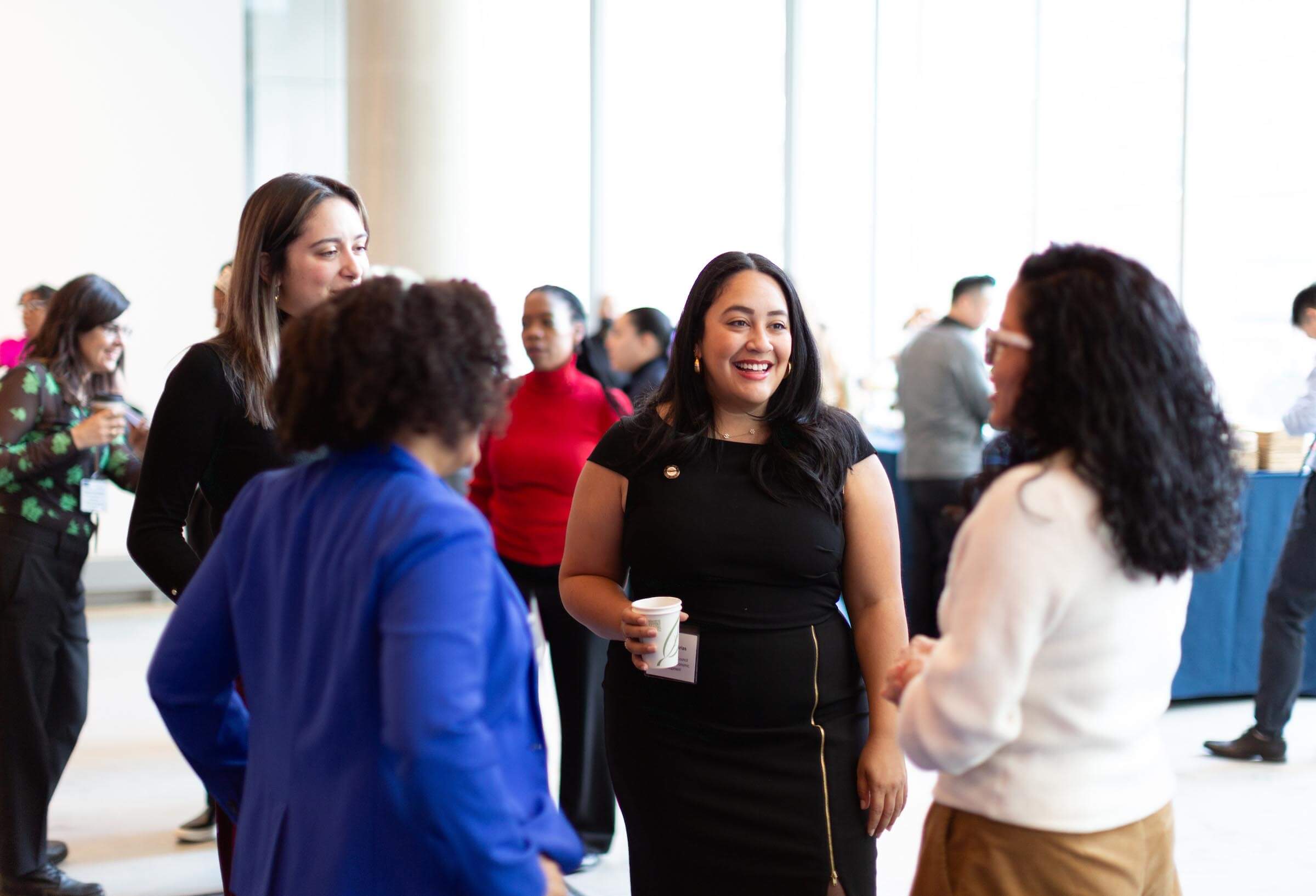 Amanda Farias stands center in a black dress with a group of professionals at the 2024 NYCETC Conference