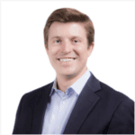 Brent Parton with short brown hair, wearing a dark blazer and light blue shirt, against a bright white background.