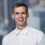 Jacob Clark with short brown hair, smiling and wearing a fully buttoned up white collared dress shirt.