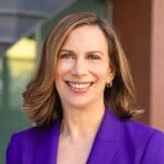 Leslie Abbey in a bright purple blazer and medium length blonde hair.